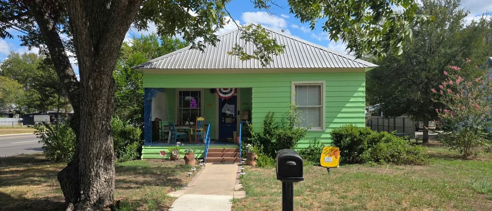 Twig Vintage Shop's bright green house on Bishop Street, with a big shade tree, a front walk and colorful chairs on the porch
