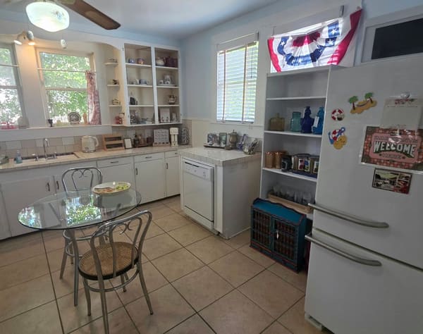 The vintage kitchen room with a glass bistro table, bentwood chairs, open shelves of glassware and patriotic bunting